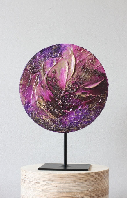 A circle pink-purple abstract painting on a sculpure pedestal.