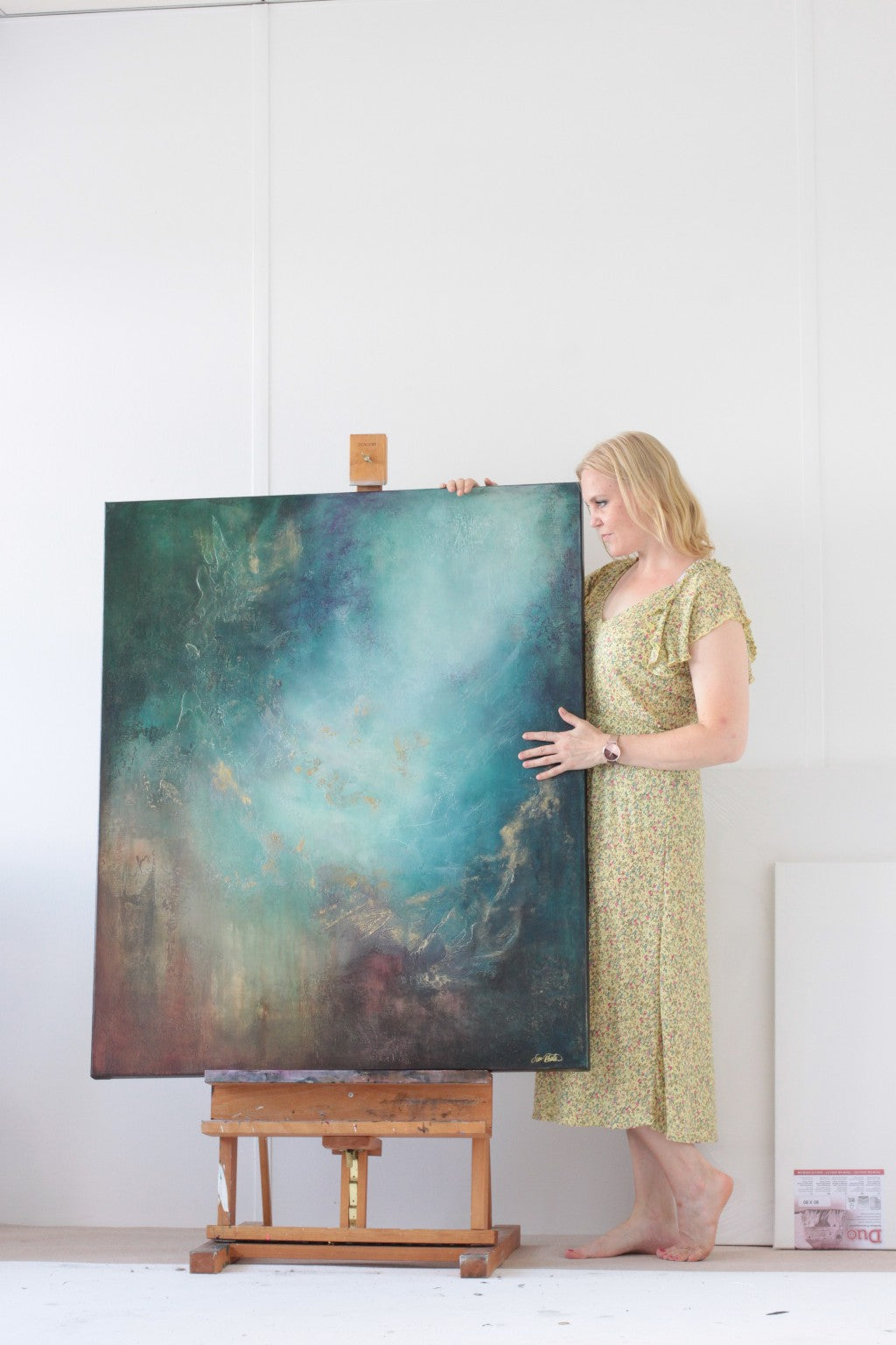 Sensitive photo of the female artist touching the large abstract painting.